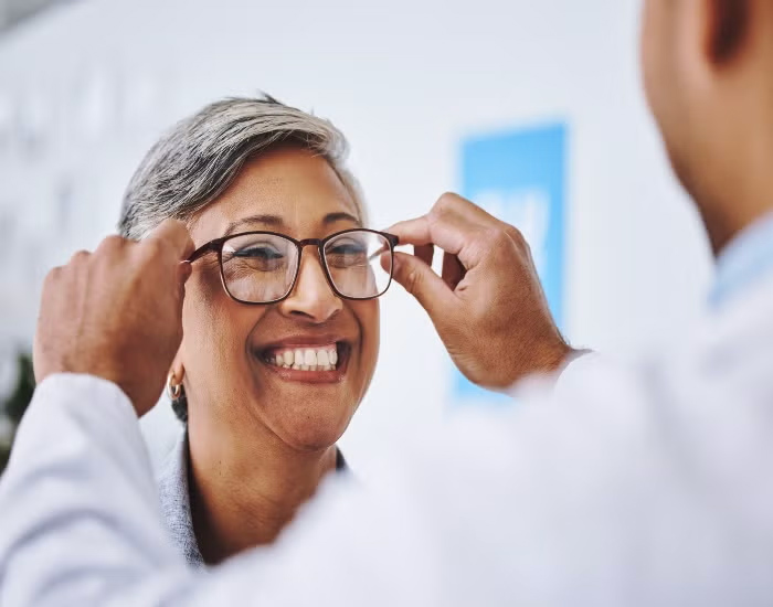 A patient tries on eyeglasses with help from an eye care professional