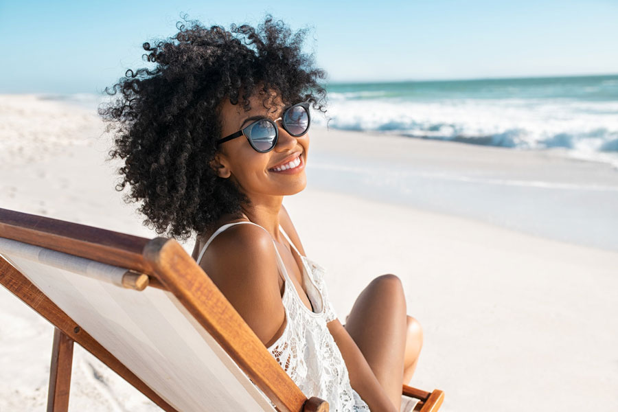 a woman wearing sunglasses sitting on a beach